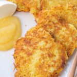 German potato pancakes served with sour cream and apple sauce on a beige plate.