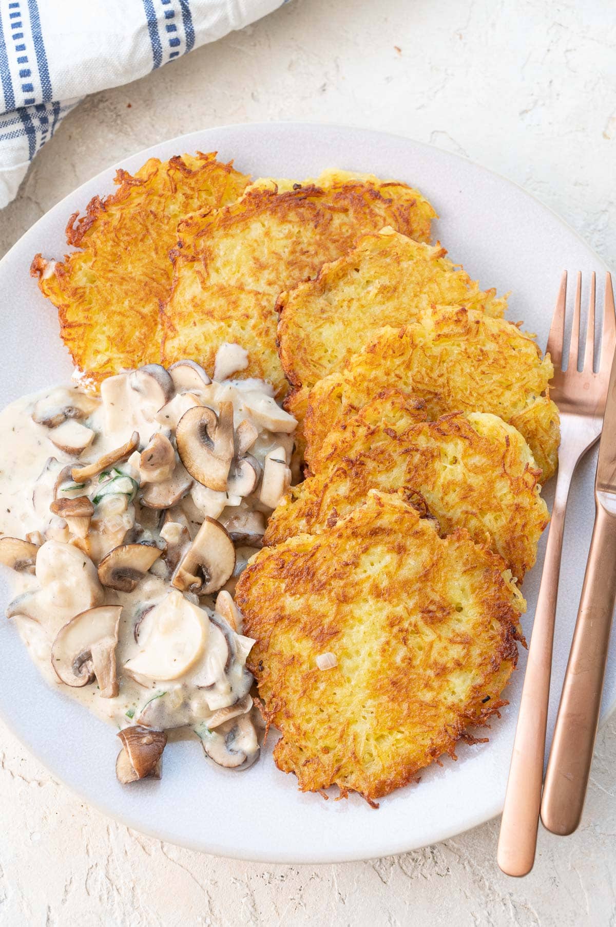 German potato pancakes with mushroom sauce on a beige plate.