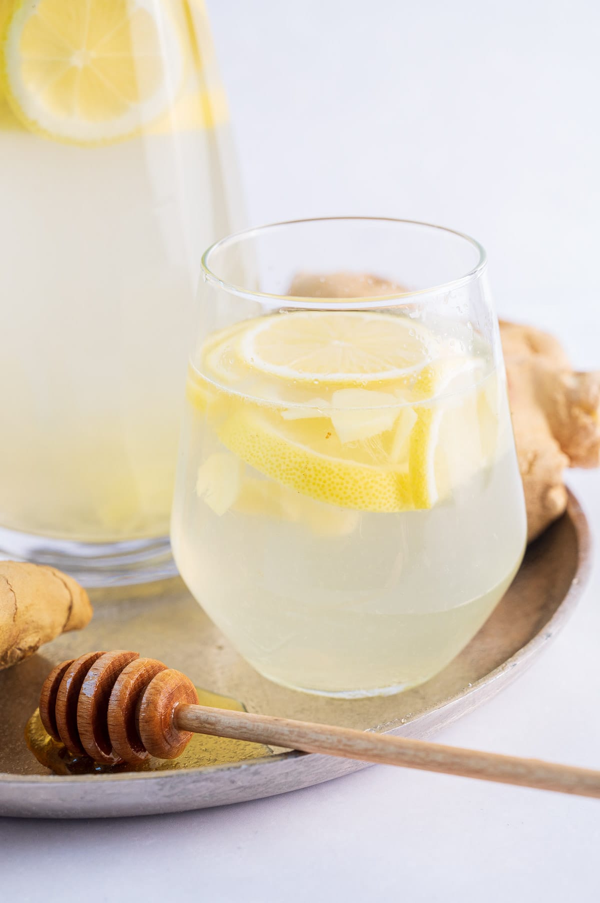 A glass with lemon ginger water on a silver tray.