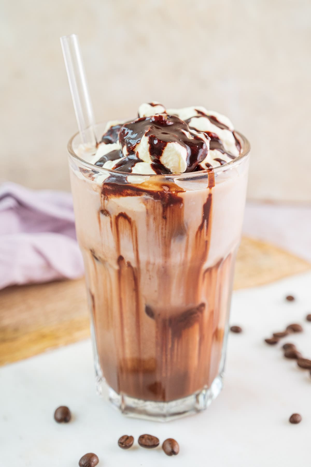 Iced mocha in a glass topped with whipped cream and chocolate syrup.