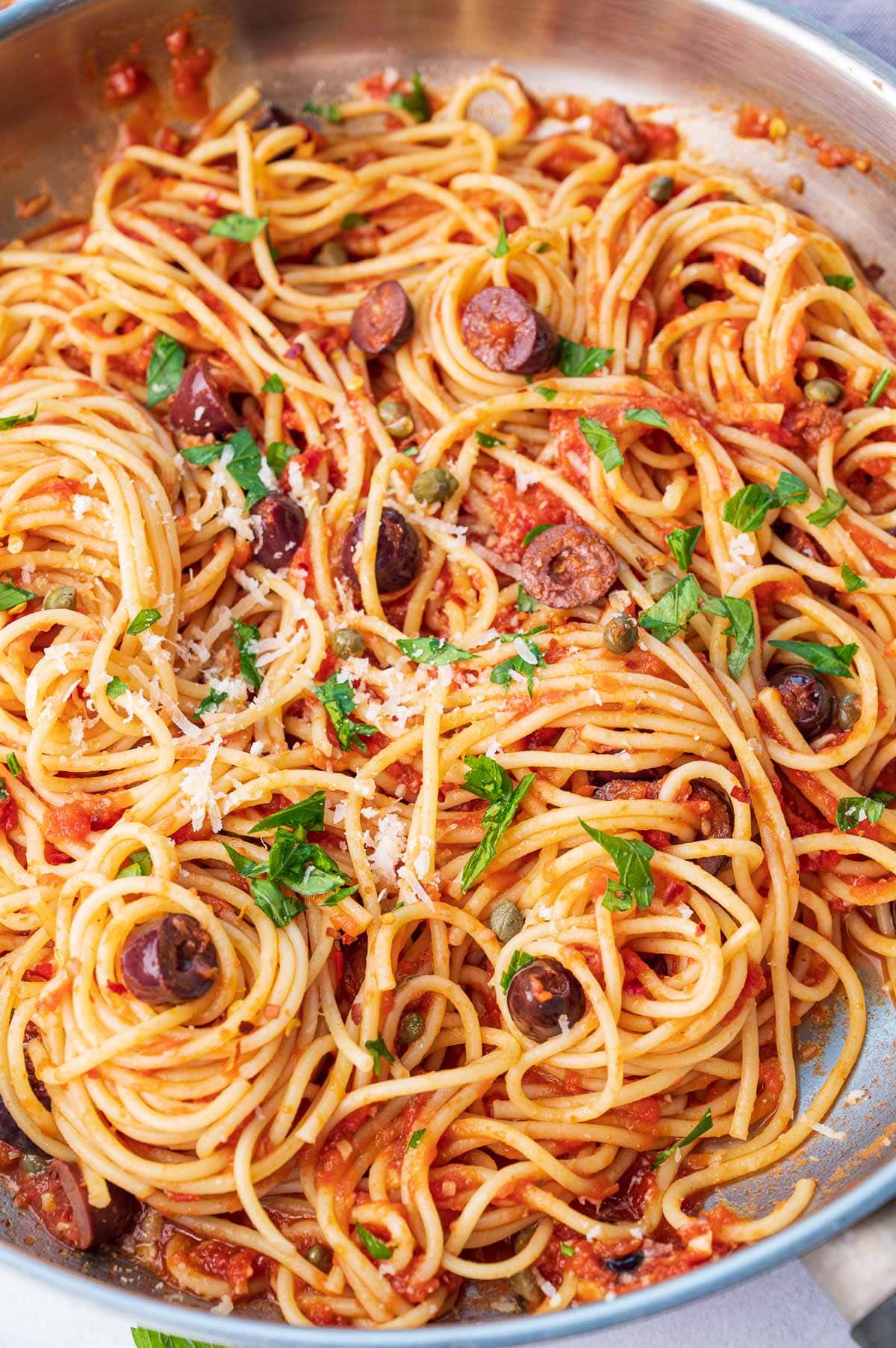 A close up photo of pasta Puttanesca in a frying pan.