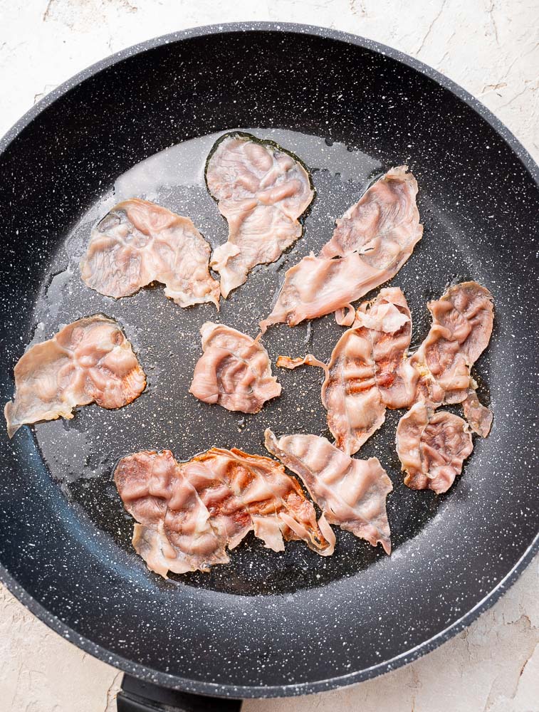 Prosciutto slices in a skillet.