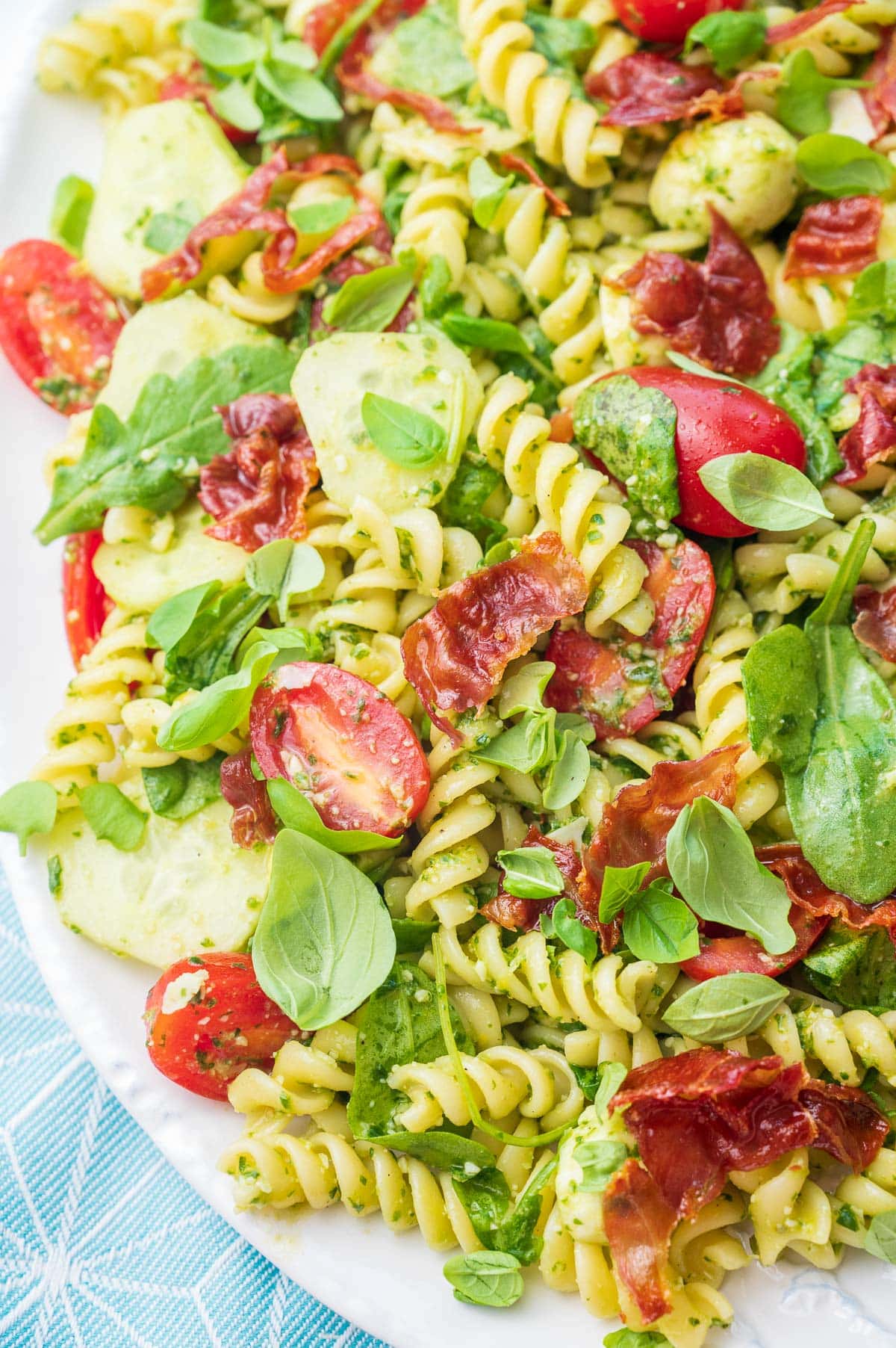 A close up photo of pesto pasta salad on a white plate.