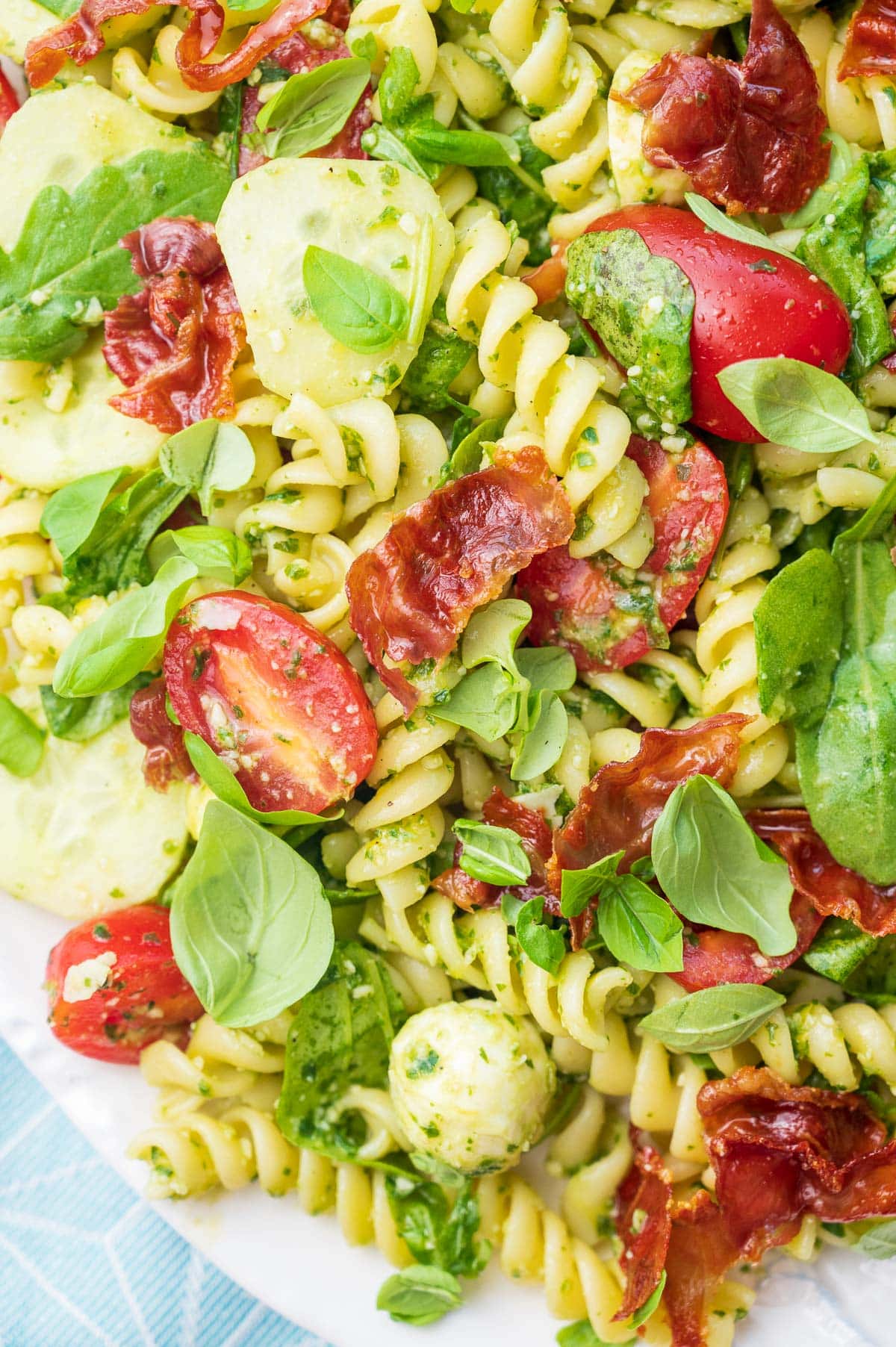 A close up photo of pesto pasta salad on a white plate.
