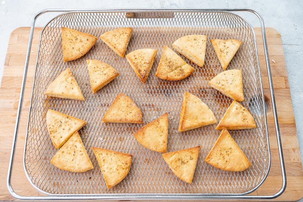 Pita chips in an air fryer basket.