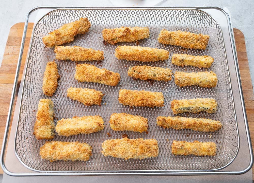 Zucchini fries in an air fryer basket.