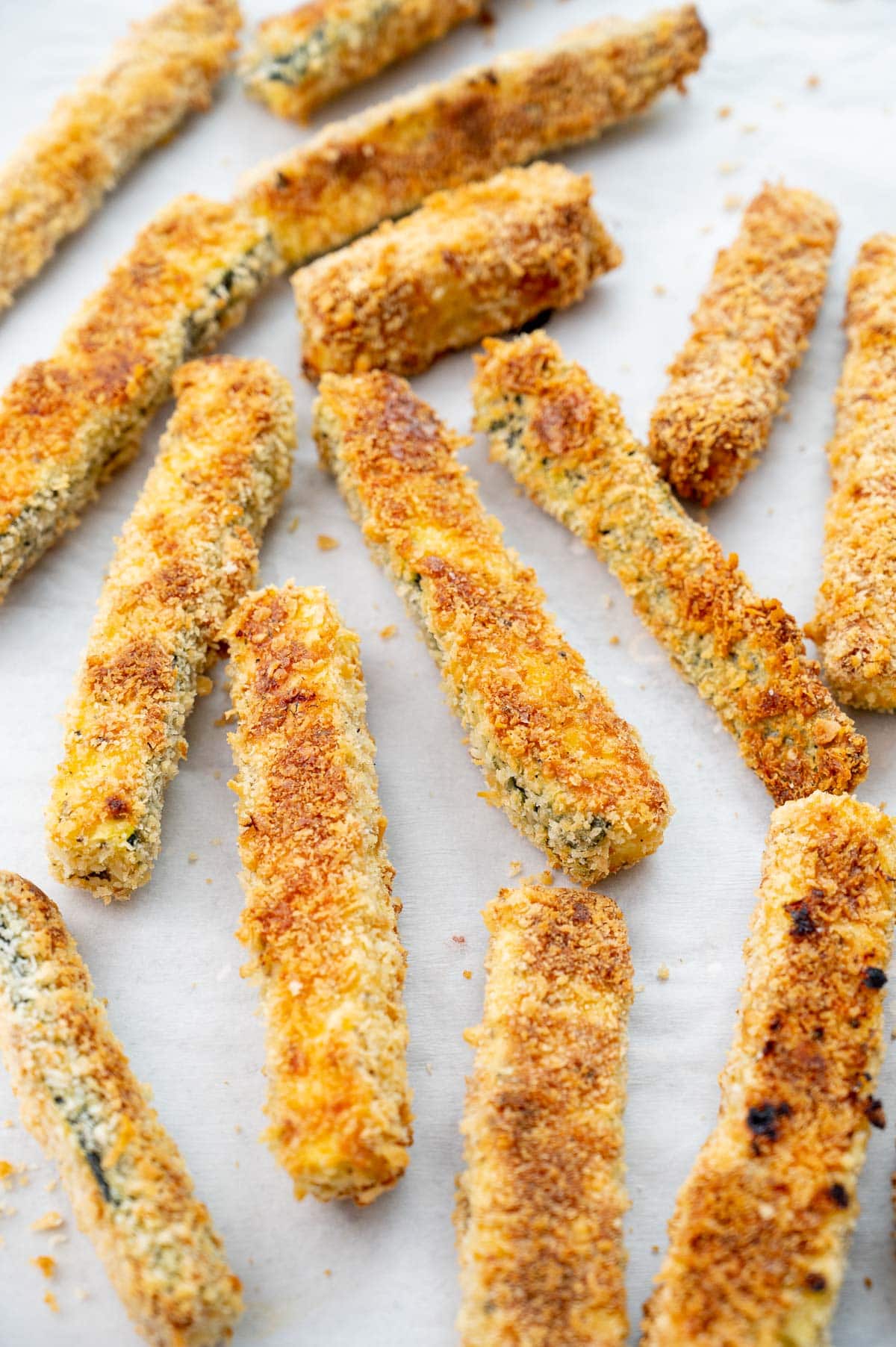 Zucchini fries on a piece of parchment paper.