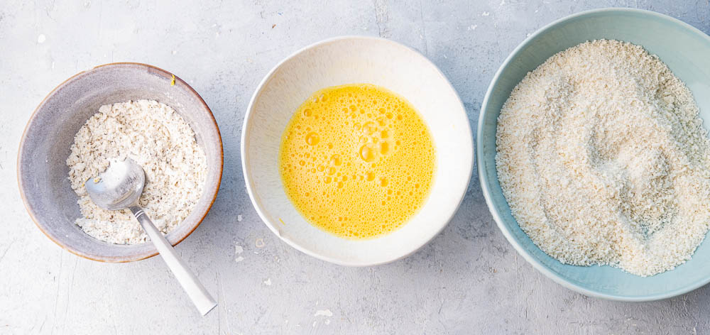 Breading station consisting of 3 plates with flour, eggs, and breadcrumbs.