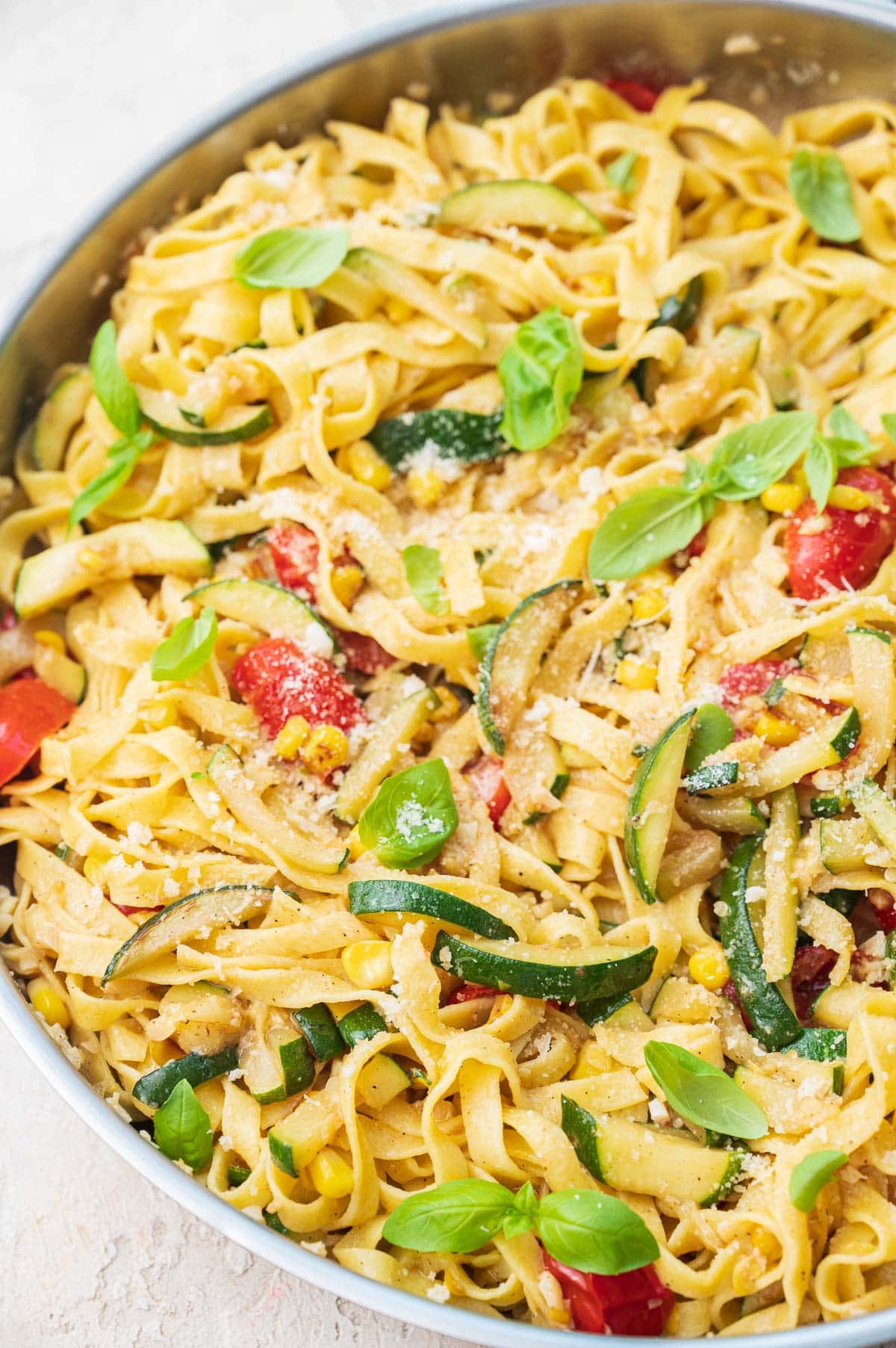 Zucchini pasta with corn and tomatoes in a frying pan.