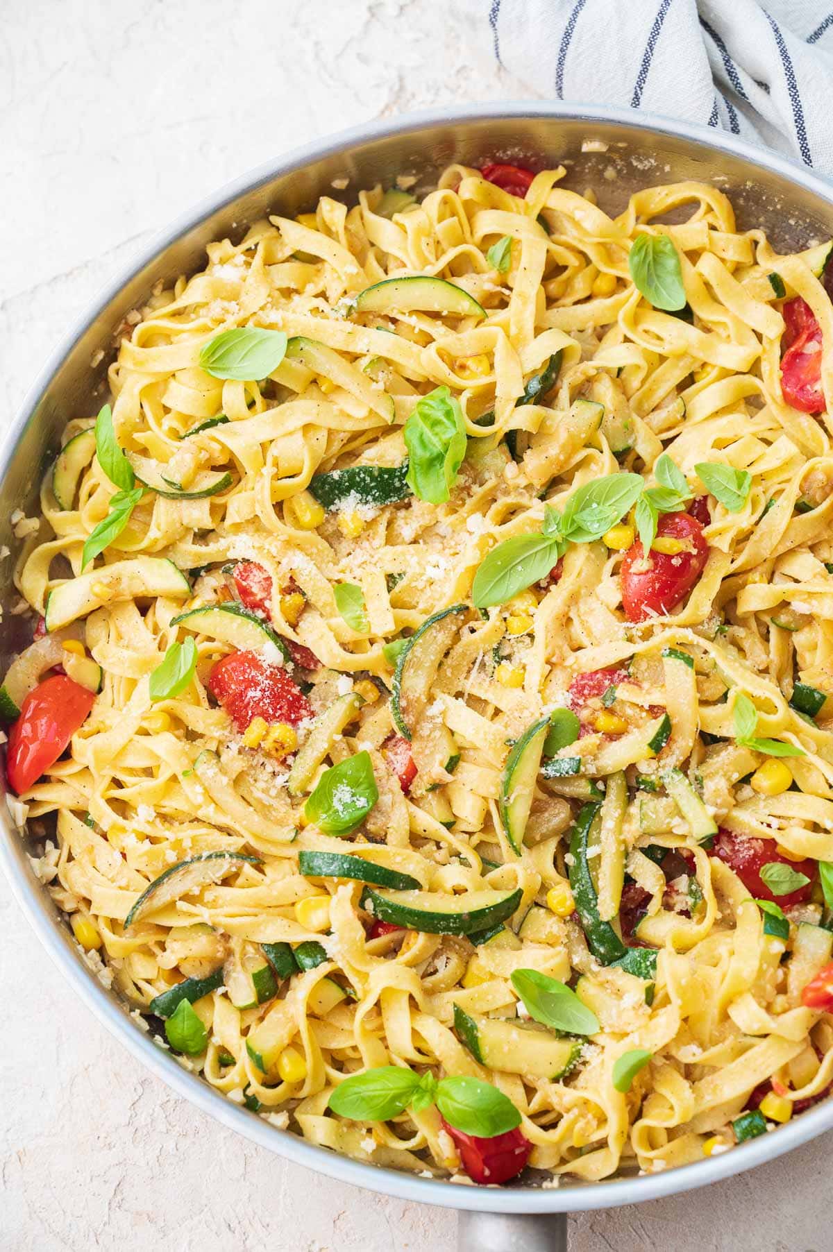 Zucchini pasta with corn and tomatoes in a frying pan.