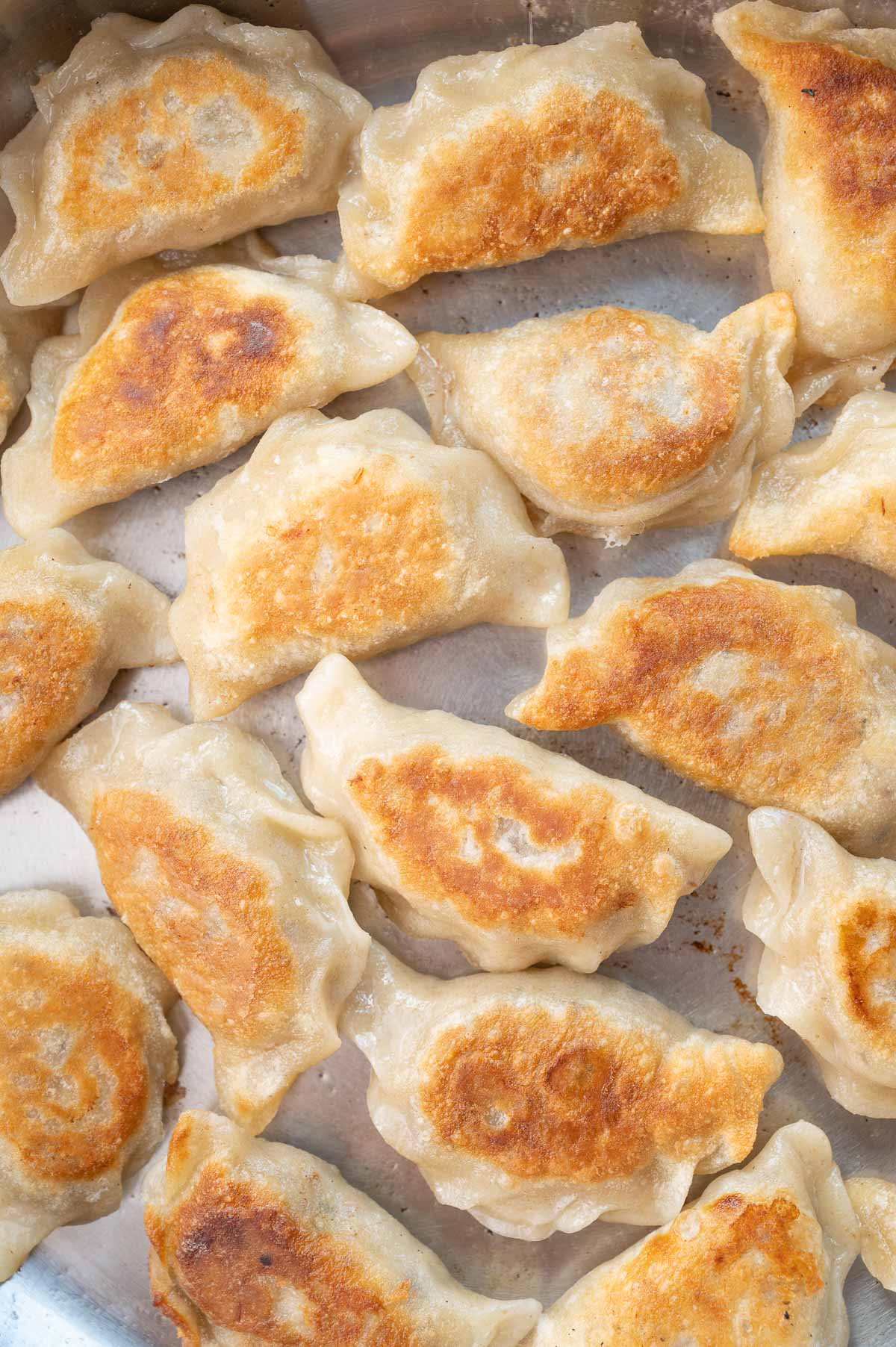 A close-up photo of pan-fried meat pierogi in a frying pan.