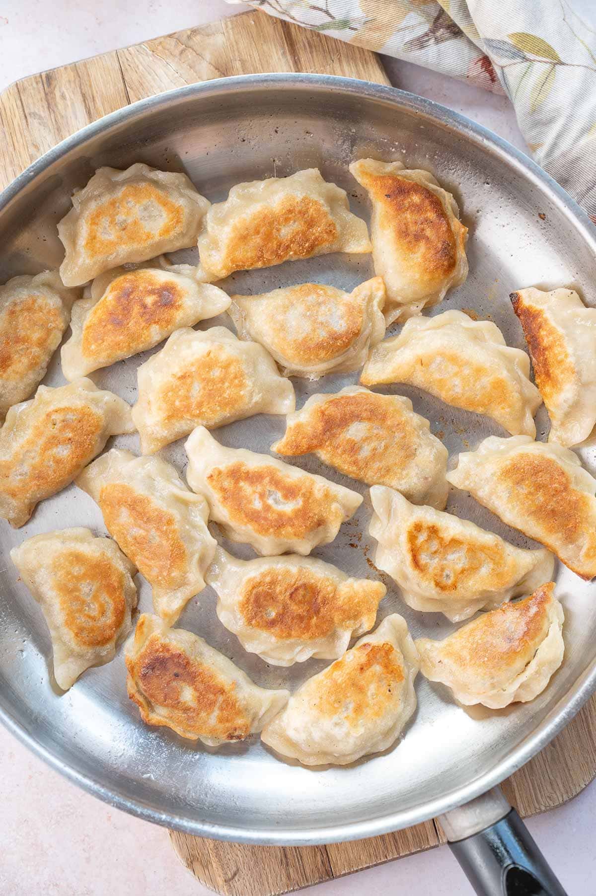 Pan-fried meat pierogi in a frying pan.