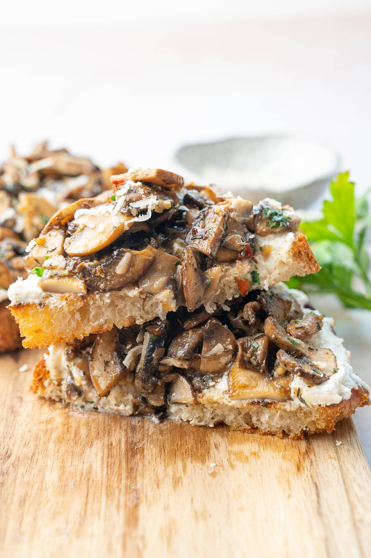 Mushroom toast cut in half on a wooden board.