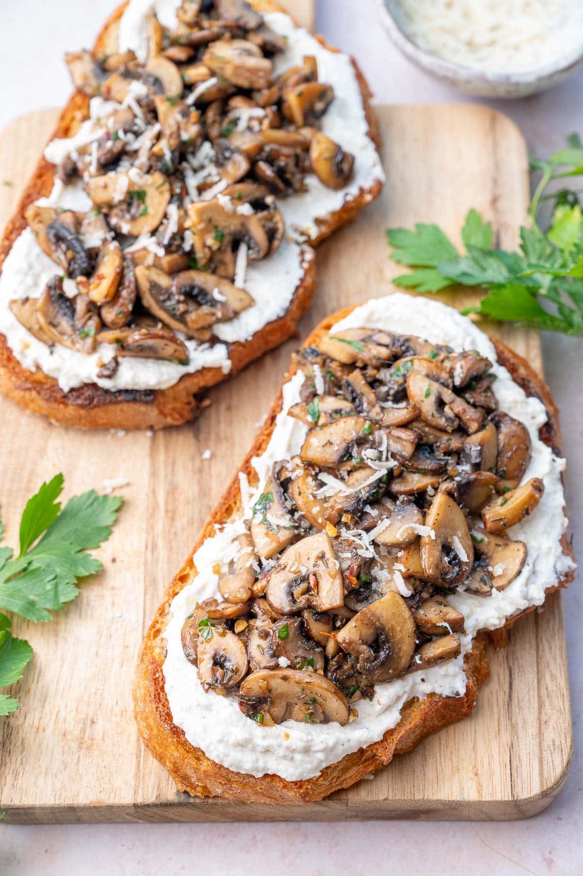 Two mushroom toasts on a wooden board.