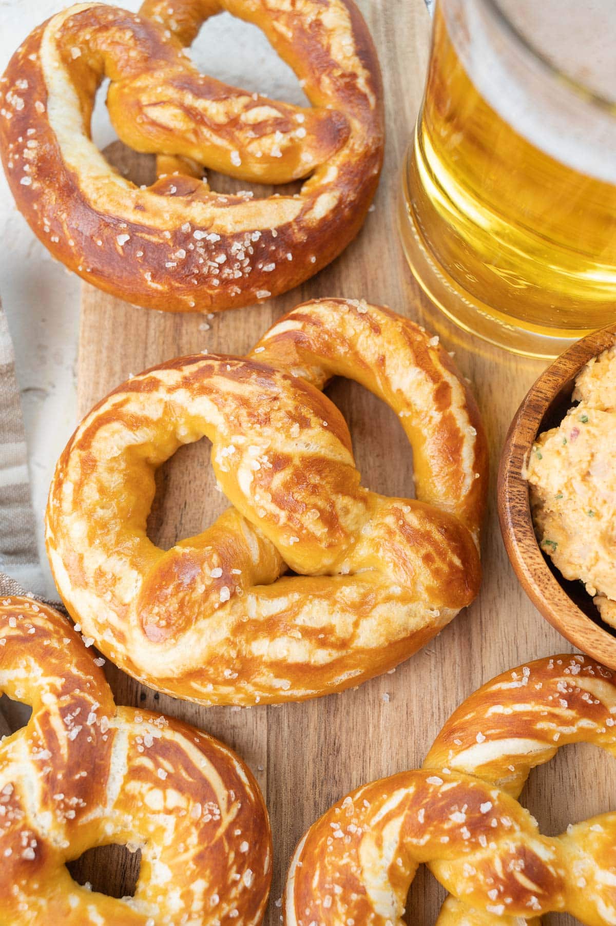 Soft pretzels on a wooden board. Beer and cheese dip on the side.