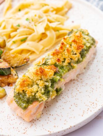 Baked pesto salmon on a white plate.