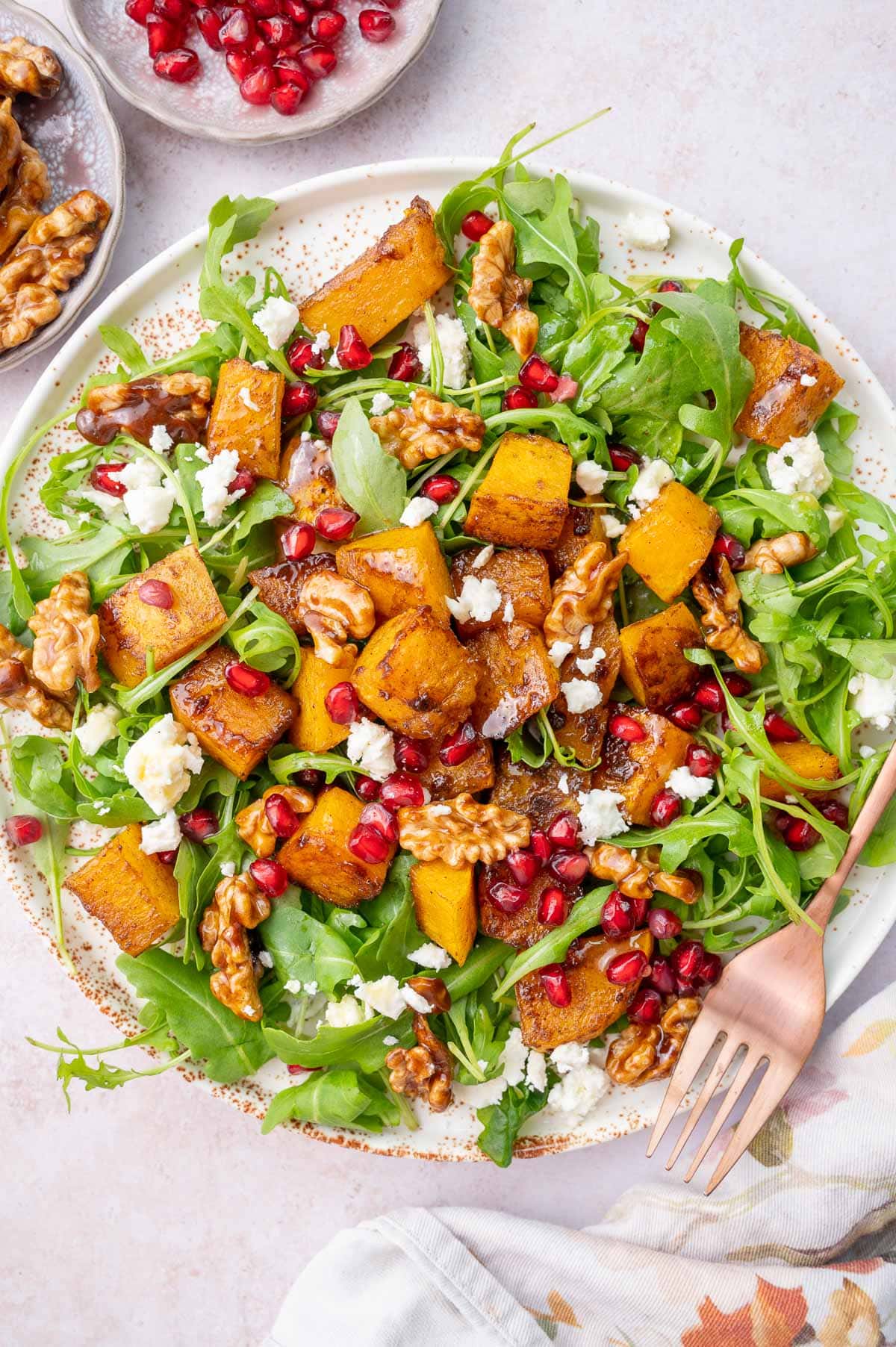 Butternut Squash Salad on a white plate with gold fork on the side.