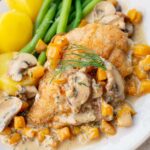 Chicken in creamy butternut squash and mushroom sauce on a beige plate.