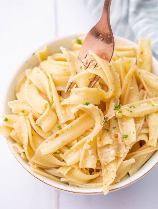 Garlic butter noodles in a white bowl.