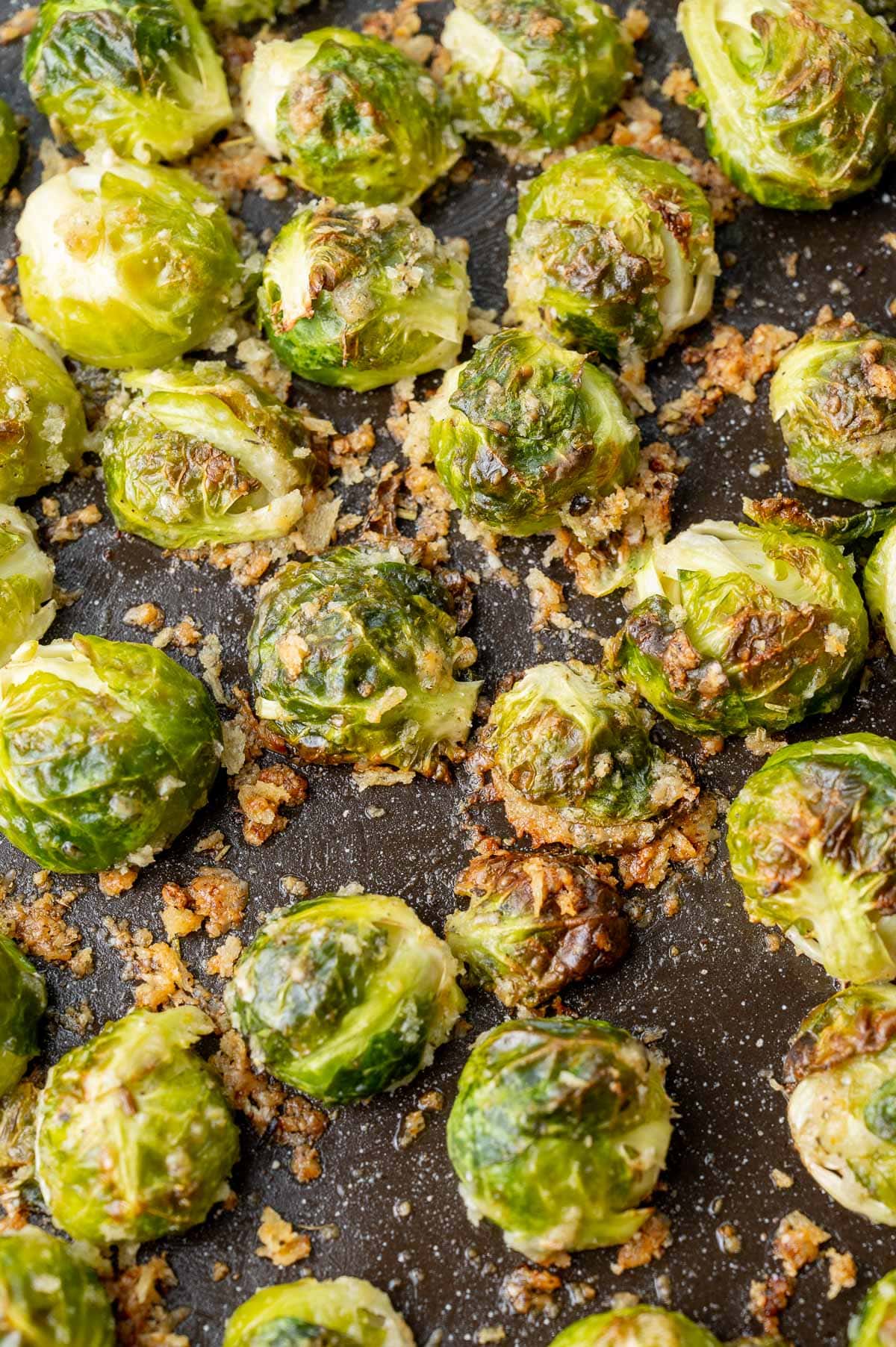 Parmesan roasted brussel sprouts on a black baking sheet.
