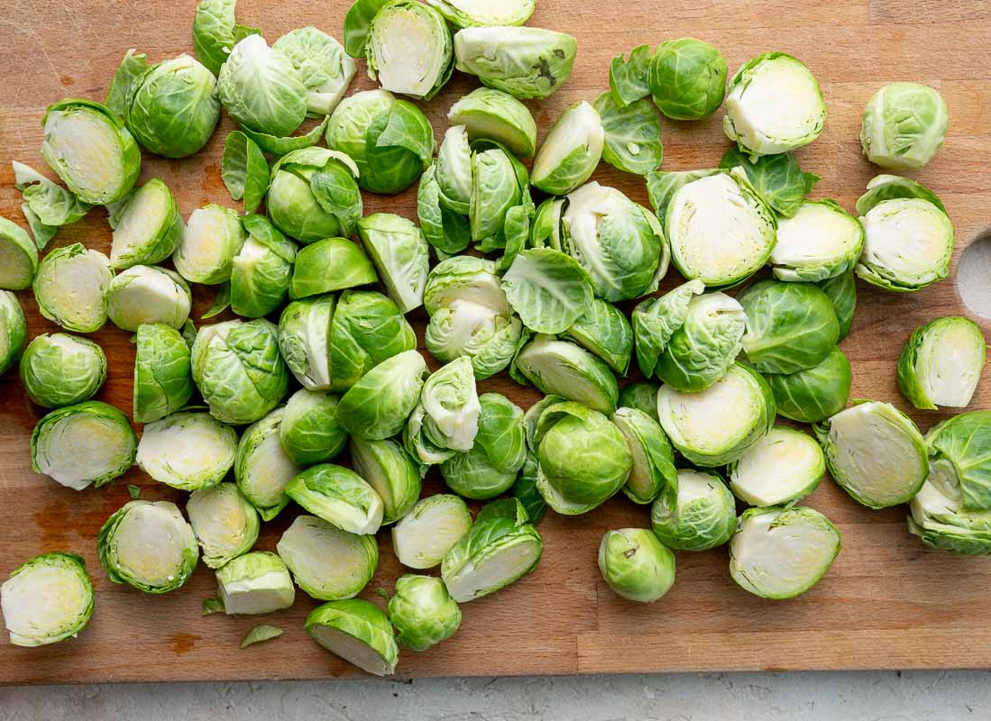 Cut in half Brussels sprouts on a wooden board.