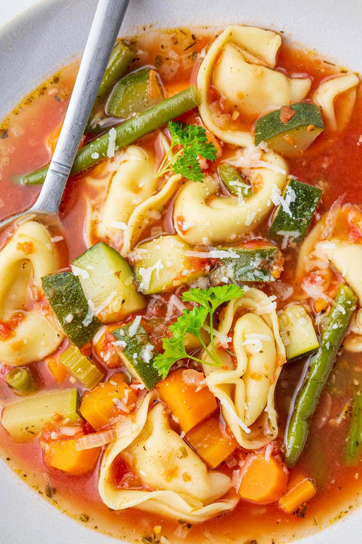 A close up photo of vegetable tortellini soup in a bowl.