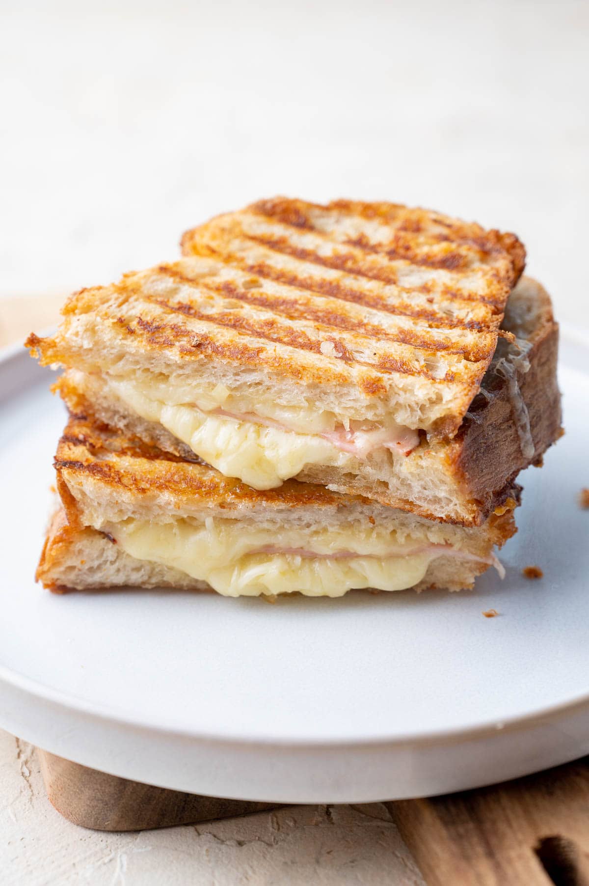 Gruyere and ham grilled cheese sandwich cut in half on a white plate.