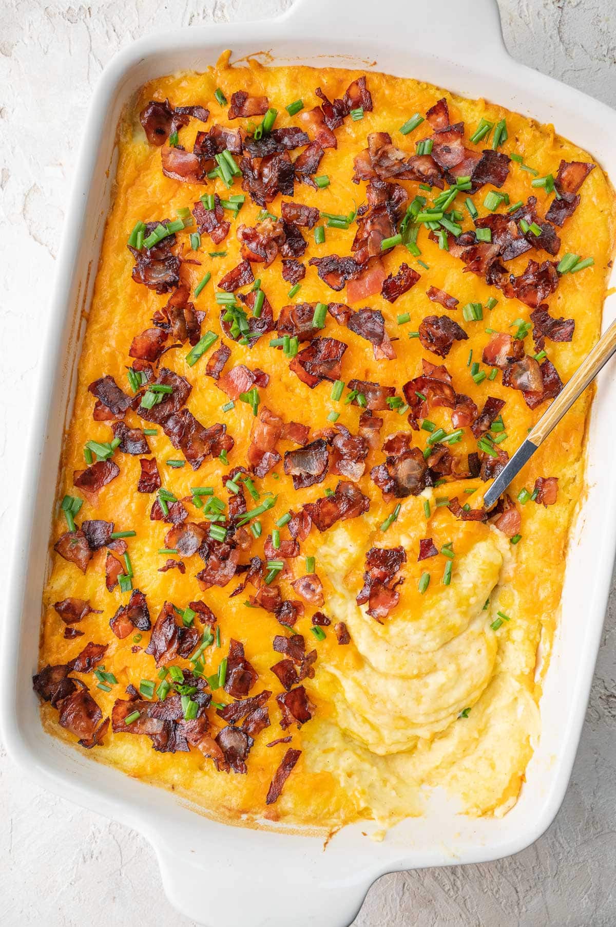 Loaded mashed potato casserole in a white baking dish.