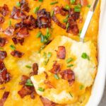 Loaded mashed potato casserole in a white baking dish.