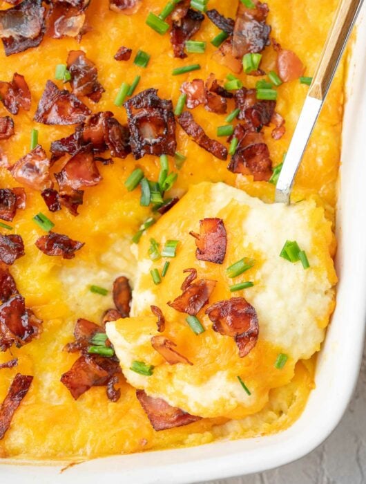 Loaded mashed potato casserole in a white baking dish.