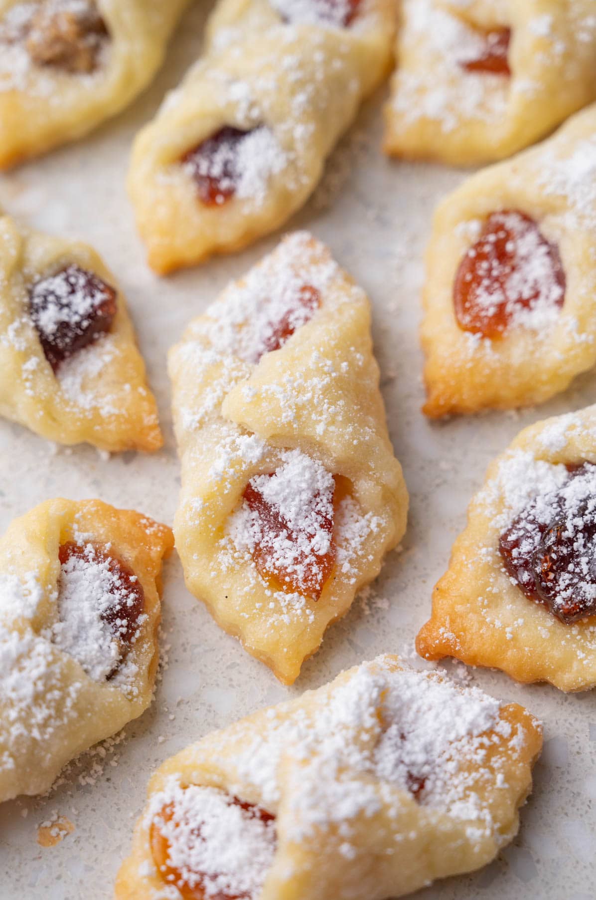 A close up picture of kolaczki cookies on a grey background.