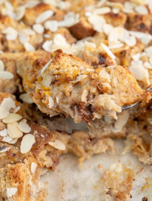 Panettone bread pudding in a baking dish and on a large spoon.