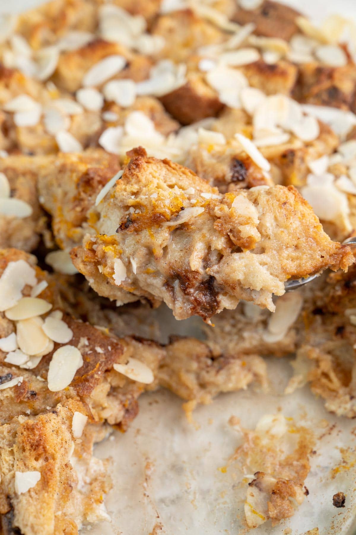 Panettone bread pudding in a baking dish and on a large spoon.