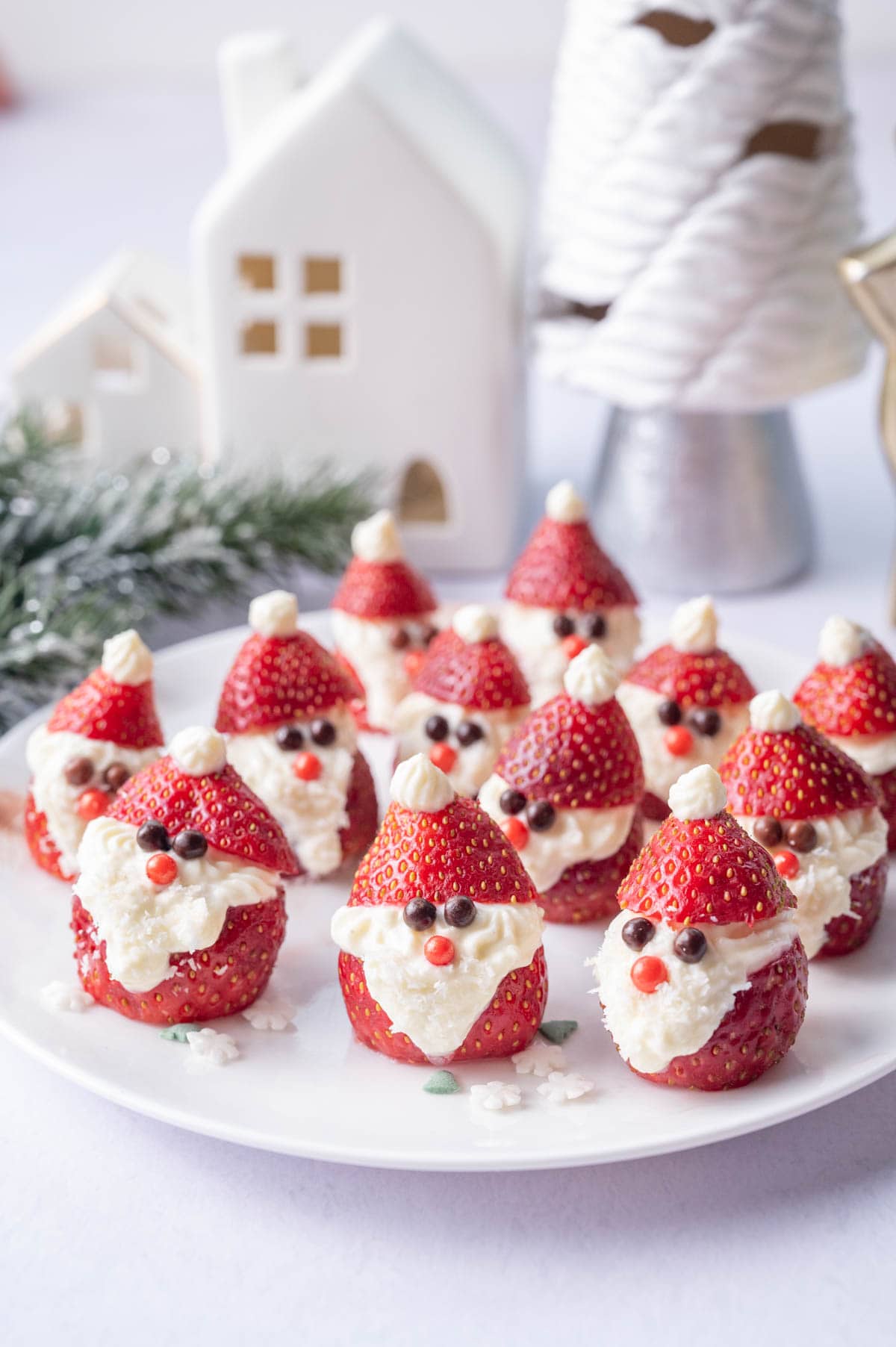 Santa strawberries on a white plate. Christmas decorations in the background.