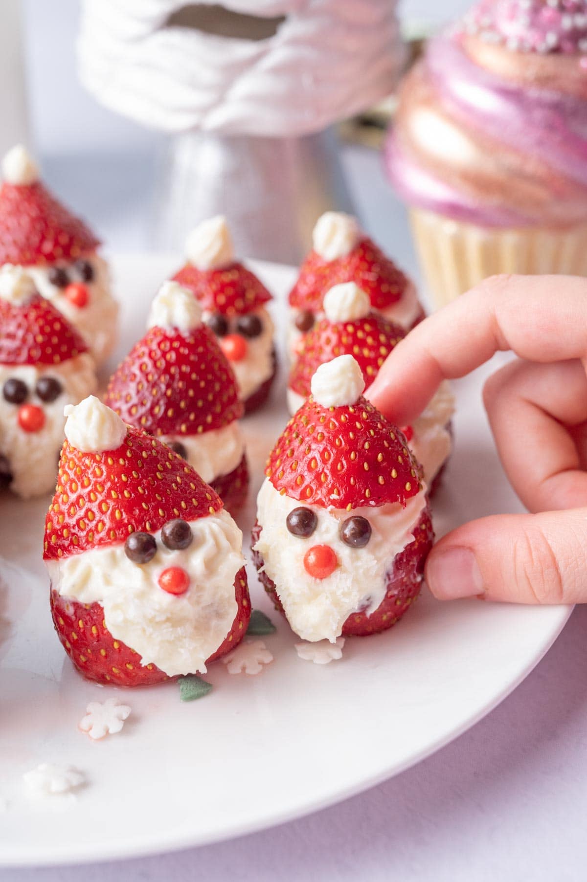 Santa strawberries on a white plate. Christmas decorations in the background.