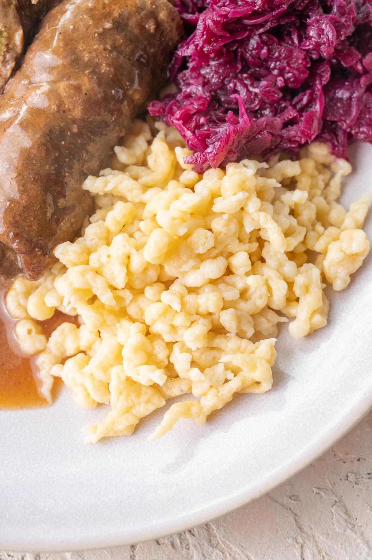 Spätzle on a plate with red cabbage and Rouladen.