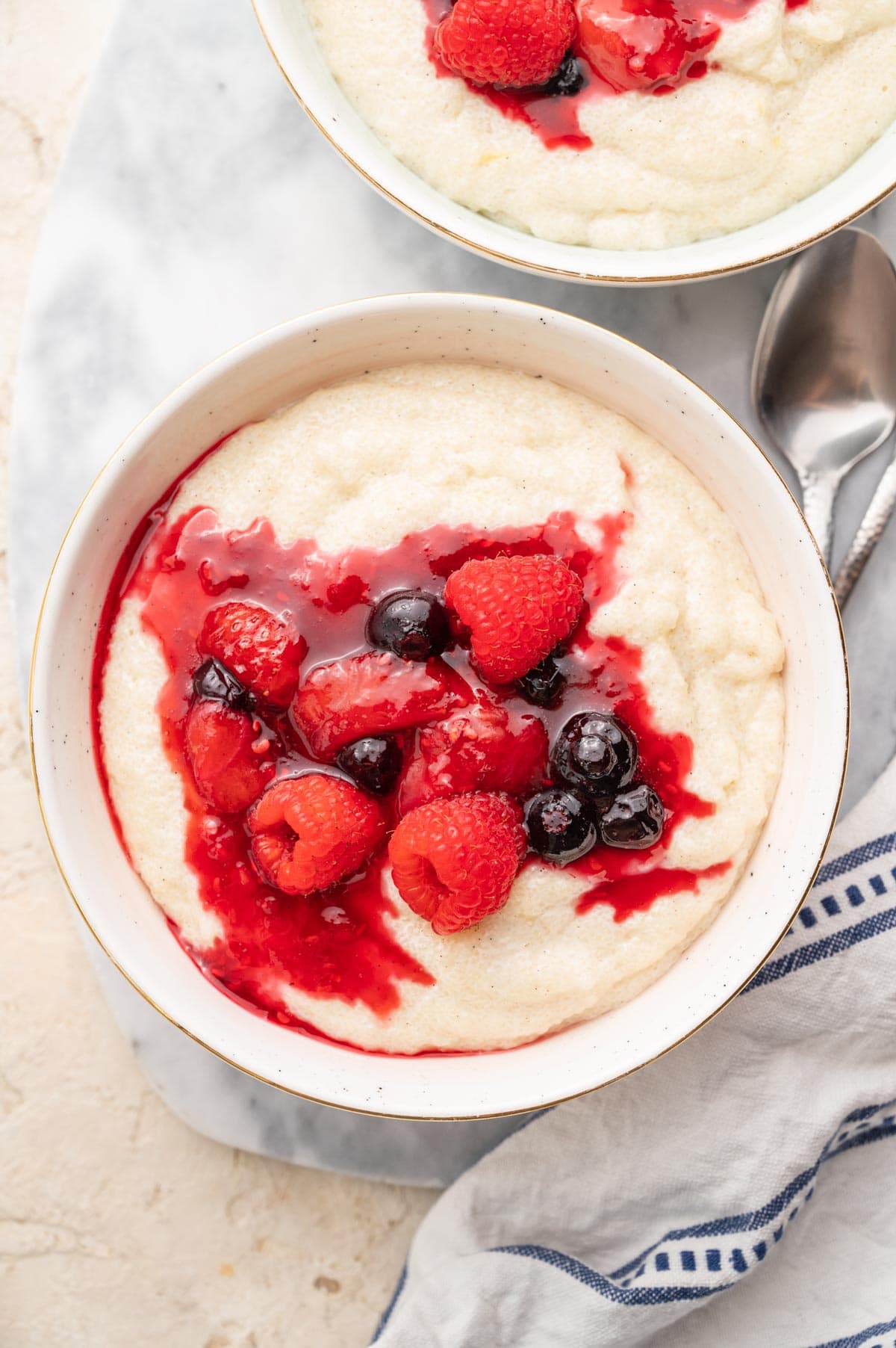 Semolina pudding with berry compote in a white bowl.