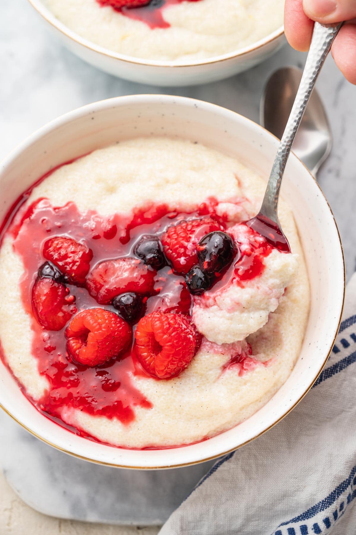 Semolina pudding with berry compote in a white bowl.