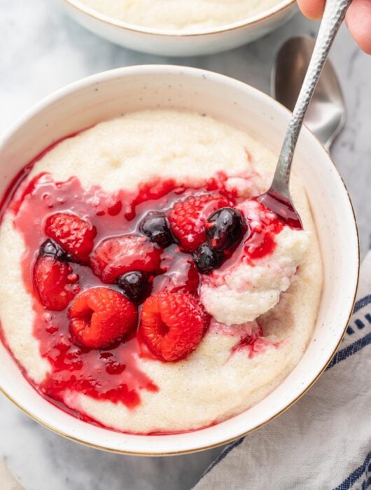 Semolina pudding with berry compote in a white bowl.