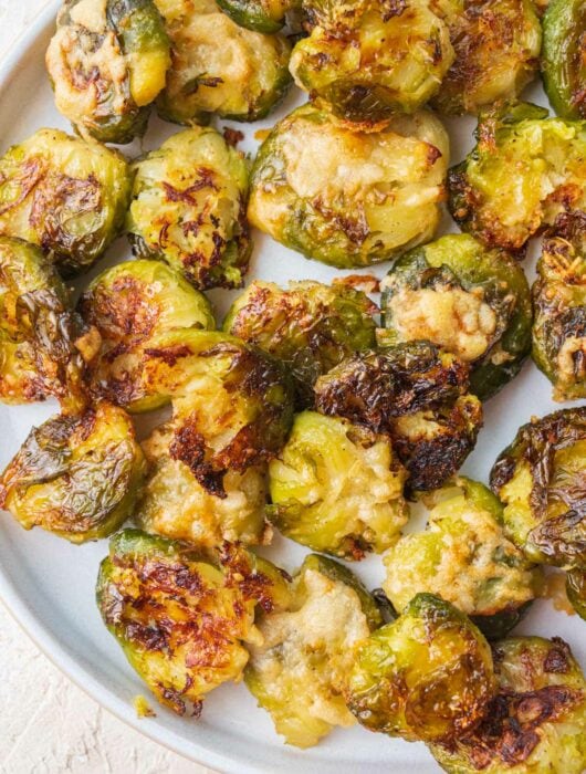 Smashed brussel sprouts on a white plate.