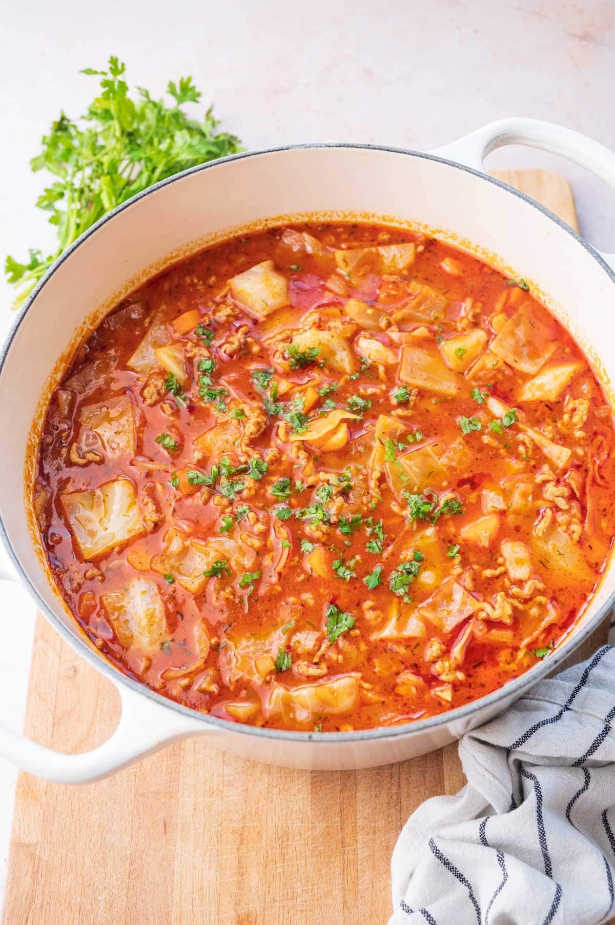 Cabbage toll soup in a big white pot on a wooden board.