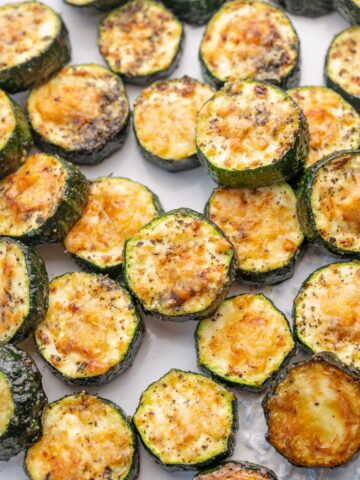Baked parmesan zucchini on a white plate.