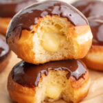 Two Boston cream donuts stack on each other.
