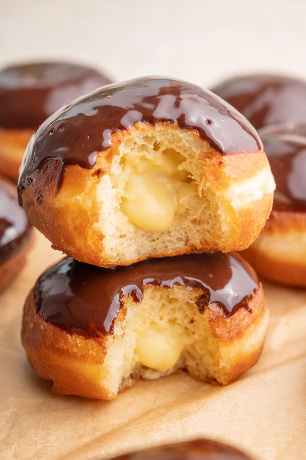 Two Boston cream donuts with a piece bitten off stack on each other.