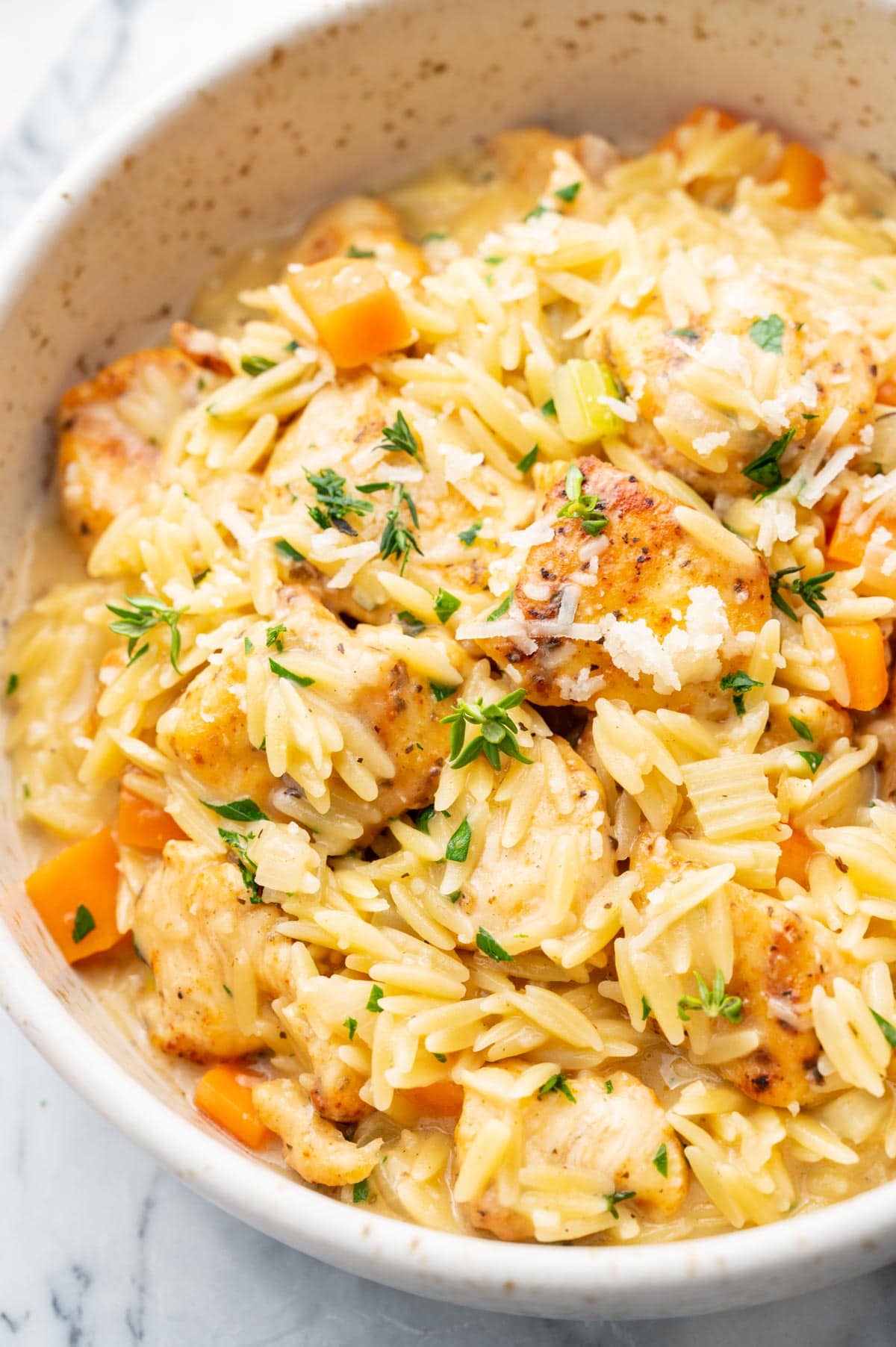 A close up photo of Creamy Chicken Orzo in a white bowl.
