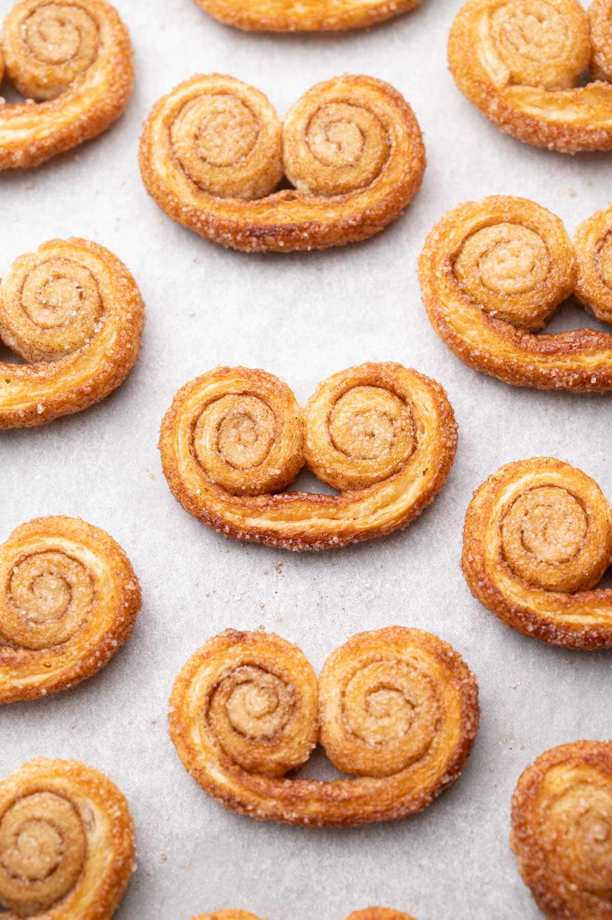 Freshly baked palmiers cookies on a baking sheet lined with parchment paper.