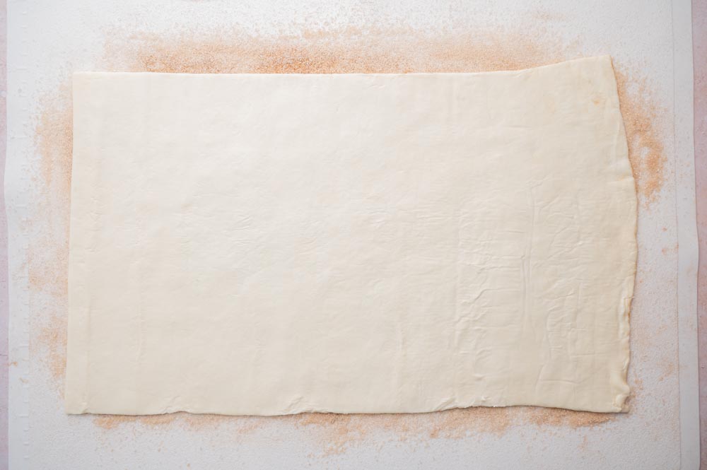 Puff pastry sheet on a white rolling mat.