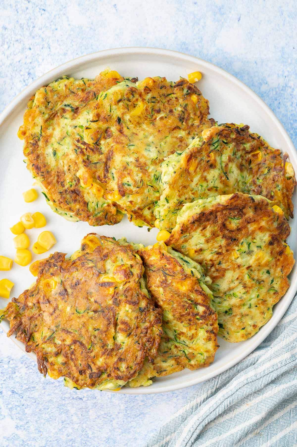 An overhead photo of zucchini corn fritters on a white plate.