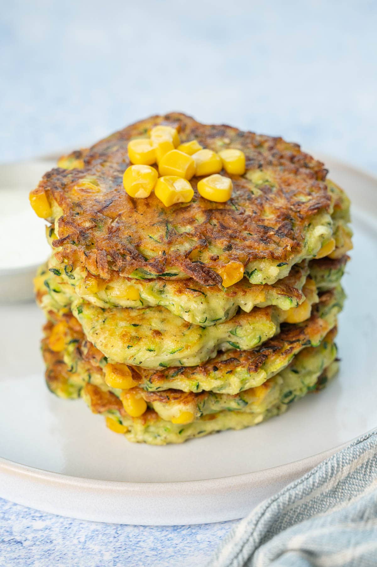 A stack of zucchini corn fritters on a white plate.