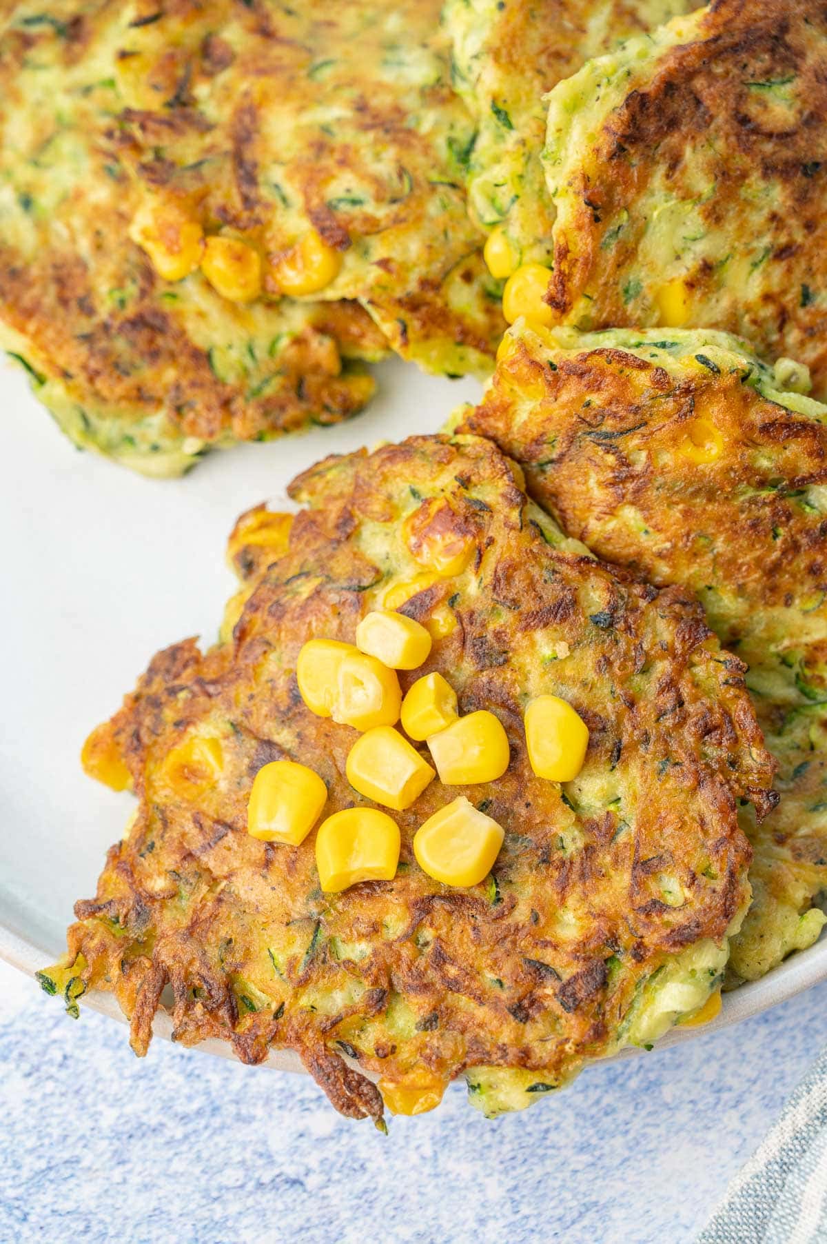 A close up photo of zucchini corn fritters on a white plate.